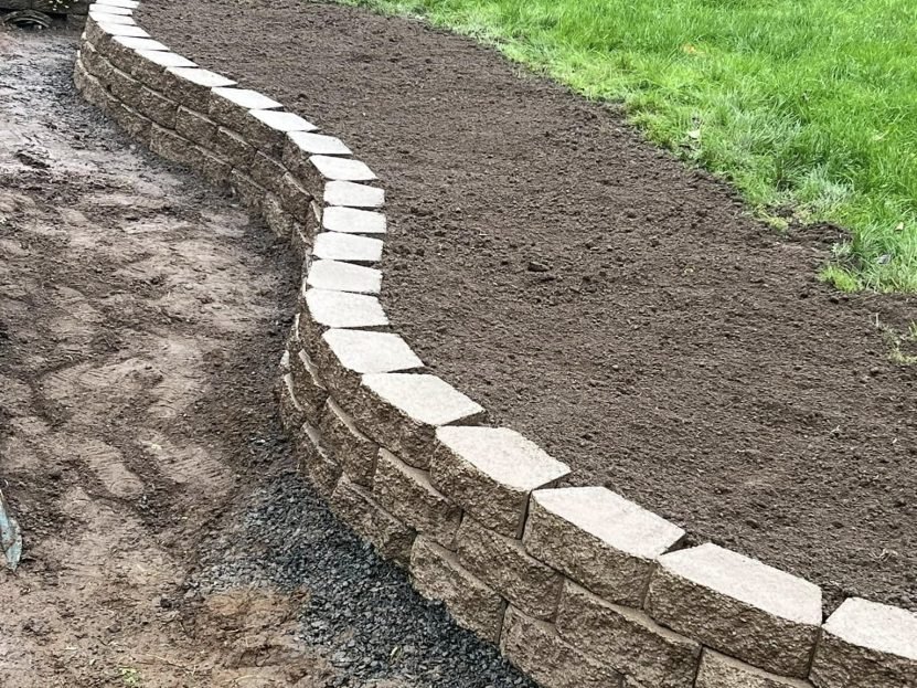 Curved stone retaining wall with a fresh mulch bed