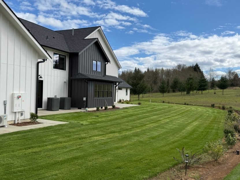Freshly mowed striped lawn beside a modern farmhouse