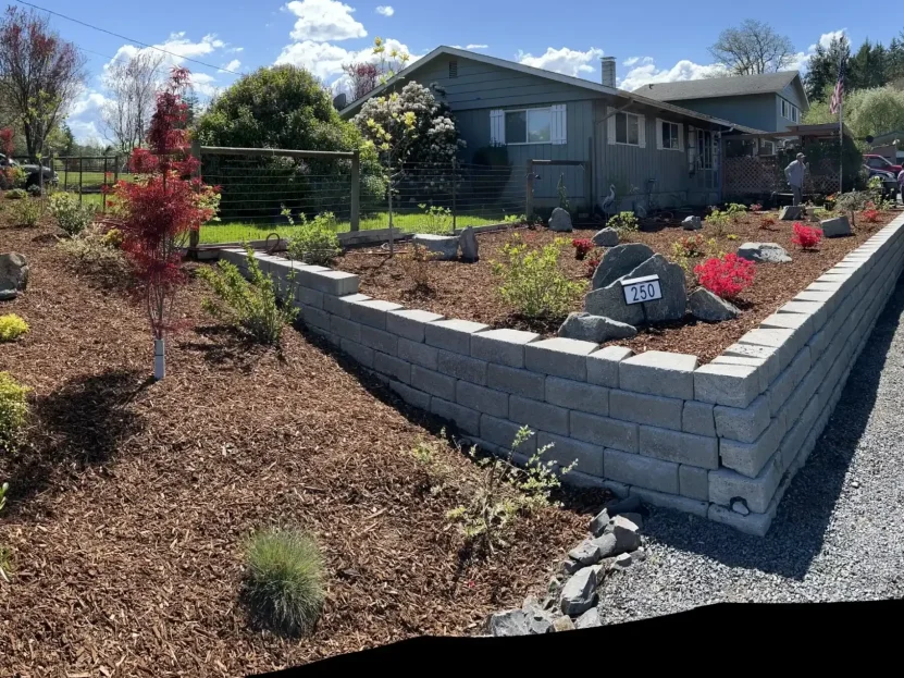Stone retaining wall with landscaping, boulders, and mulch